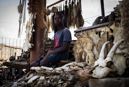 Thierry Alimantin, adolescente beninés, posa con los distintos fetiches que vende en su puesto de Akodessewa. El turismo era otra vía de ingresos de los comerciantes, pero las restricciones de movimiento impuestas para contener la pandemia de covid-19 ha hecho descender el número de visitantes a Togo y, por tanto, el mercado recibe menos atención.