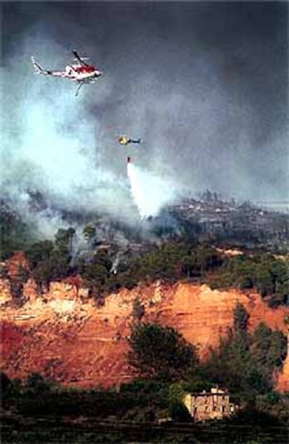 Medios aéreos trataban ayer de controlar el incendio en una zona forestal de La Riba.