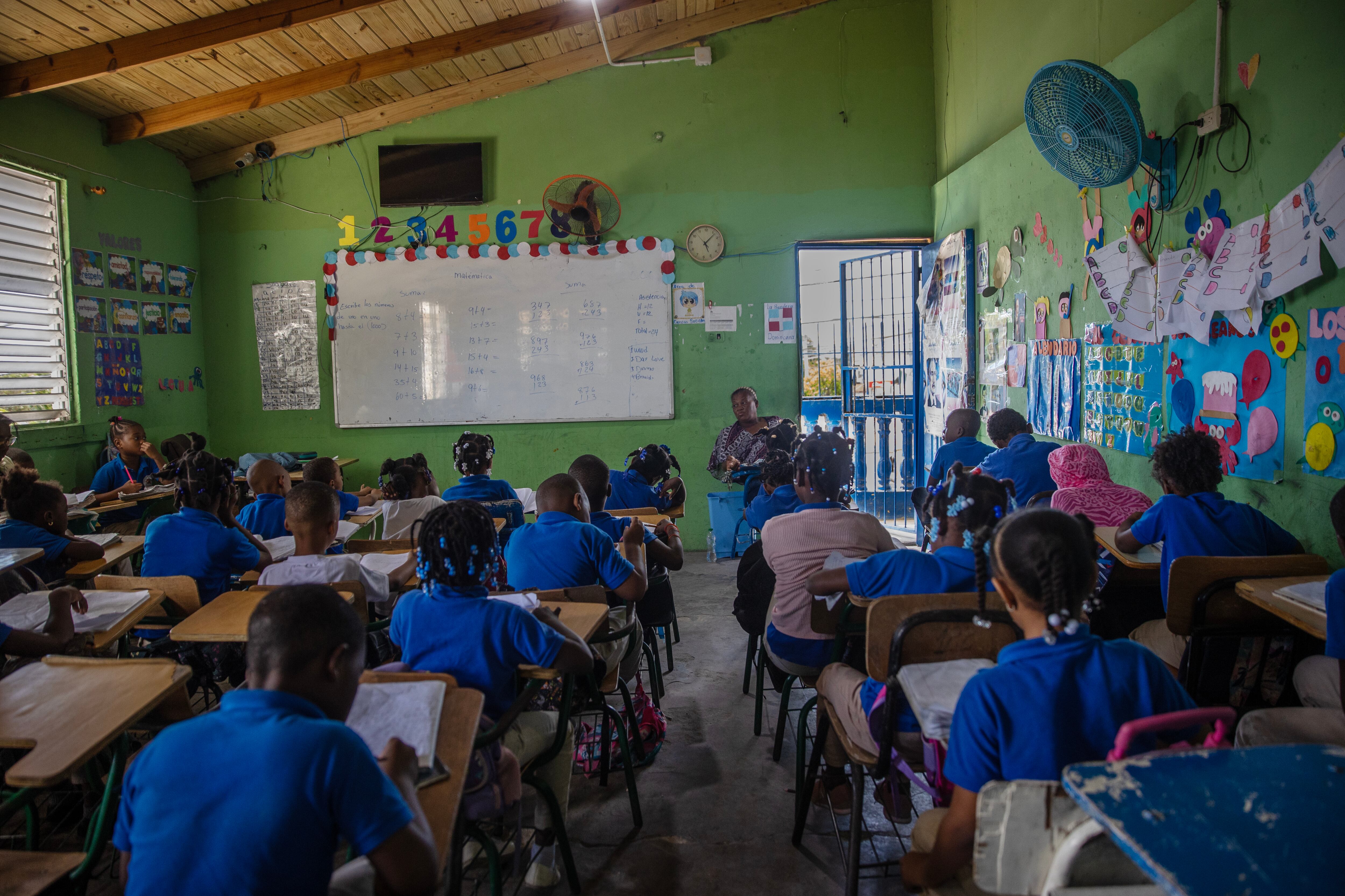 Decenas de niños toman clase en una escuela de Villa Esperanza, en la zona de Friusa, donde más de la mitad de los alumnos haitianos han dejado de asistir a clases en las últimas semanas.