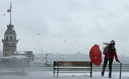 La autoridades municipales han informado de que se han registrado en Estambul desde el martes 841 accidentes de tráfico y han pedido a los conductores que sean especialmente prudentes. En la imagen, una mujer intenta controlar su paraguas en medio de una racha de viento mientras camina a orillas del Bósforo durante una nevada en Estambul (Turquía).