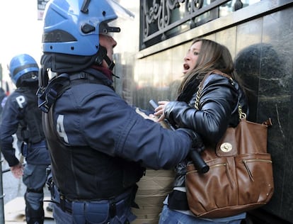 Un policía retiene contra una pared a una mujer durante la manifestación de estudiantes en Turín.