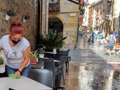 Una trabajadora desinfecta la mesa de la terraza un local de hostelería.