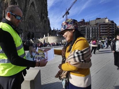 Un mosso repartint díptics a una turista a la Sagrada Família.