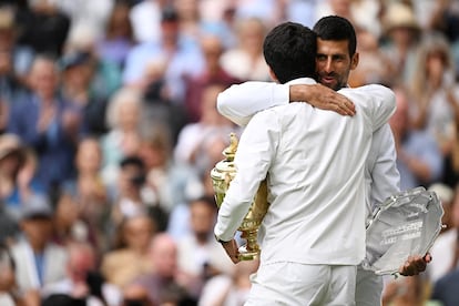 Djokovic y Alcaraz (de espaldas) se abrazan tras la entrega de  trofeos en la pista central del club londinense. 
