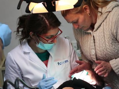 Un madre ayuda a su hijo en el dentista solidario de la Ca&ntilde;ada Real, en Madrid. 