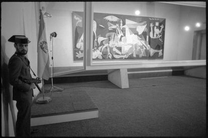 Con la llegada de la democracia, el 'Guernica' de Picasso fue devuelto a España en 1981. En la imagen puede verse en su primer emplazamiento, en el Casón del Buen Retiro de Madrid, custodiado por la Guardia Civil, protegido por una urna de cristal antibalas y acompañado de la bandera preconstitucional. Desde 1992 se exhibe en el Museo Reina Sofía de Madrid.