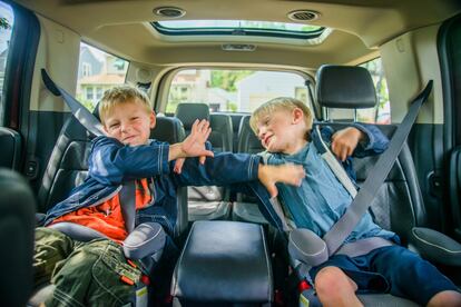 Dos hermanos se pelean en el coche. 