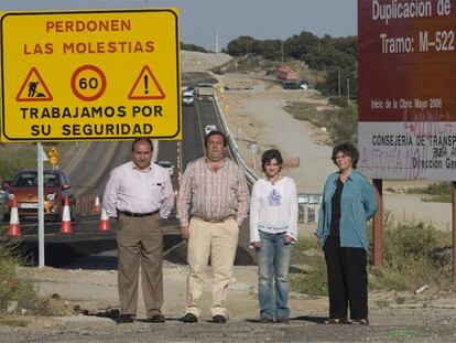 De izquierda a derecha, los alcaldes Pablo Martín (San Martín de Valdeiglesias) y Mario de la Fuente (Robledo de Chavela) y las ecologistas María Ángeles Nieto (Ecologistas en Acción) y Concha Velasco (Organización Sierra Oeste Desarrollo SOStenible) ante los carteles que avisan de las obras de duplicación en la <i>carretera de los pantanos.</i>