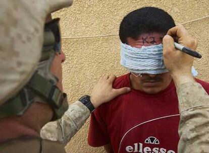 Un <i>marine</i> estadounidense rotula un número en la frente de un prisionero, detenido en Haditha (Irak), en mayo de 2005.