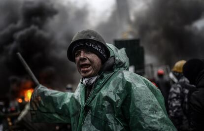 Un manifestante ucranio grita a sus compañeros detrás de barricadas durante los enfrentamientos con la policía.