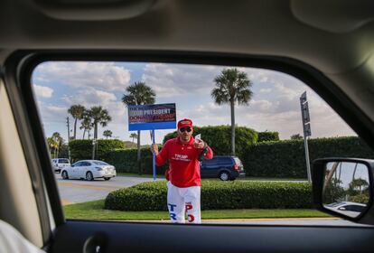 Un partidario del candidato presidencial republicano Donald Trump es visto con una pancarta apoyándolo, en Palm Beach, Florida.