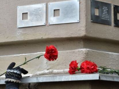 Una mujer pone flores bajo una placa en Mosc&uacute;.