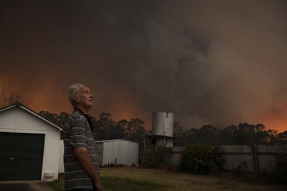 Un hombre observa desde su jardín el horizonte en llamas causado por el incendio de Green Wattle Creek, al oeste de Sídney.