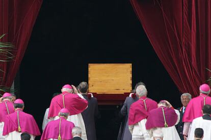 Los cardenales, vestidos con el color del luto papal (rojo), acompañan el féretro de Juan Pablo II para la ceremonia privada del enterramiento en la cripta de la basílica de San Pedro.