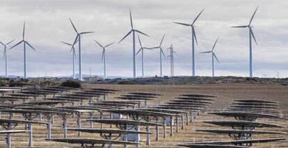 Una planta solar, en primer plano, y aerogeneradores de energía eólica, al fondo.