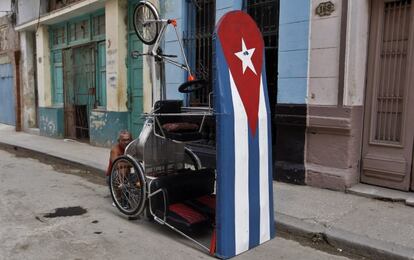 Un hombre repara su bicitaxi, que tiene la bandera nacional cubana pintada en el techo durante la primera de las tres jornadas de luto por la muerte de Castro.