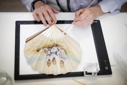 Limpieza de un abanico con una fotografía impresa coloreada con los hijos de Alfonso XII y su esposa, Victoria Eugenia, en el Taller de porcelana y vidrio de Patrimonio Nacional, en el Palacio Real de Madrid, el 29 de mayo.