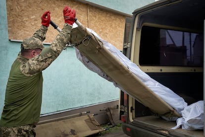 Ukrainian soldier loads the bodies of killed Ukrainian servicemen