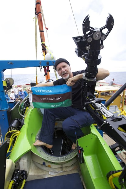 El cineasta James Cameron sostiene la bandera de la National Geographic Society tras completar con éxito su inmersión en la fosa de las Marianas.