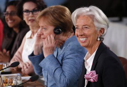 La directora del FMI, Christine Lagarde, sonríe mientras la canciller alemana, Angela Merkel se coloca los auriculares, durante un almuerzo el 9 de junio de 2018.