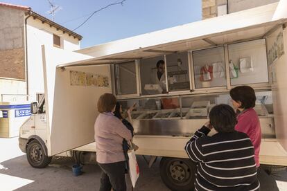 Varias vecinas de Bello, Teruel, compran el pescado a Santiago Ruiz, un pescadero que visita el pueblo una vez por semana.