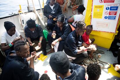 Un grupo de migrantes desayuna en la cubierta del barco.