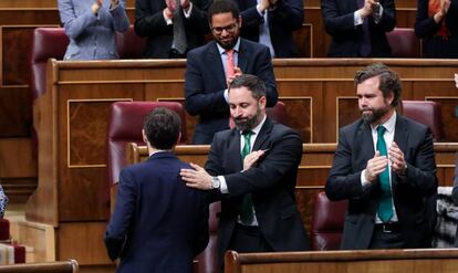 El presidente de Vox, Santiago Abascal, da una palmada en la espalda en señal de reconocimiento al portavoz de Unión del Pueblo Navarro (UPN) en el Congreso, Sergio Sayas, tras su intervención.