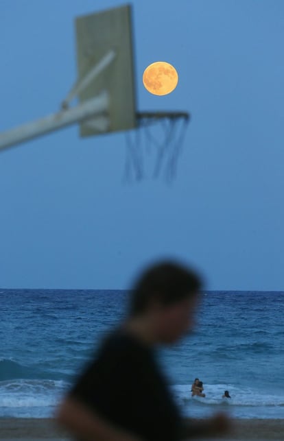 Un hombre corre por la playa de San Juan de Alicante bajo la 'superluna', en Valencia.