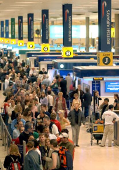 Decenas de viajeros se agolpan ante los mostradores de British Airways en el aeropuerto de Heathrow esta mañana.