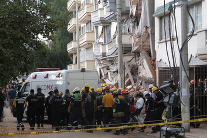 Una ambulancia forense traslada un cuerpo rescatado de un edificio colapsado.