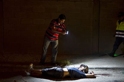 Un investigador forense fotografía el cuerpo sin vida de Ruberman Ramos, de 36 años, después de haber sido atacados por unos asaltantes no identificados en San Pedro Sula, Honduras, el 24 de marzo de 2013.
