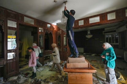 Un hombre trata descolgar una lámpara de cristal de la residencia privada de El Asad en Damasco. 