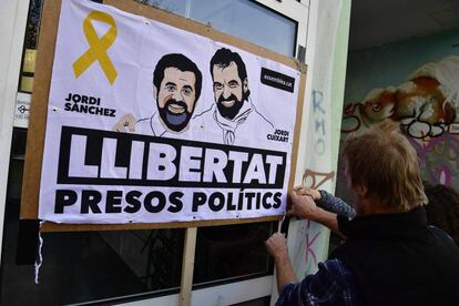 Un hombre coloca una pancarta con los rostros de Jordi Sànchez y Jordi Cuixart en Berlín el 7 de abril.