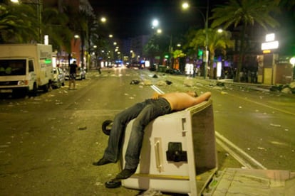 Un turista duerme sobre un contenedora en Lloret de Mar tras la batalla campal registrada durante la madrugada.