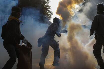 Un manifestante contra el gobierno lanza una granada de gas lacrimógeno hacia los policías durante los enfrentamientos.