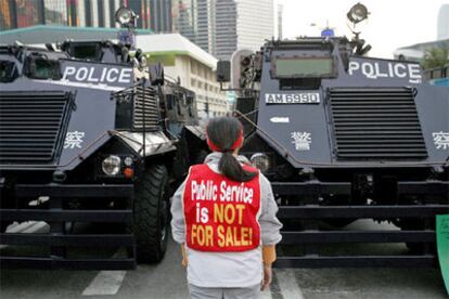 Una granjera surcoreana protesta ante dos blindados de la policía antidisturbios durante una manifestación contra la celebración de la cumbre de la OMC en Hong Kong.