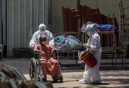 Dos trabajadores sanitarios atienden a una paciente sospechosa de tener el coronavirus, en el centro de covid-19 en Bombay. China, Pakistán, Emiratos Árabes y Australia, entre otros países, han ofrecido ayuda a la India, que todavía ve lejos el momento en el que logrará doblegar esta curva de contagios.