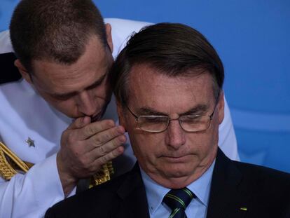 Un militar habla al oído de Bolsonaro en una ceremonia en Brasilia el pasado marzo.