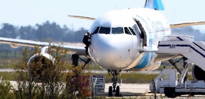 Una persona, que se cree podría ser miembro de la tripulación, sale por una ventana de la cabina del avión de EgiptAir secuestrado por un pasajero en el aeropuerto de Larnaca (Chipre).