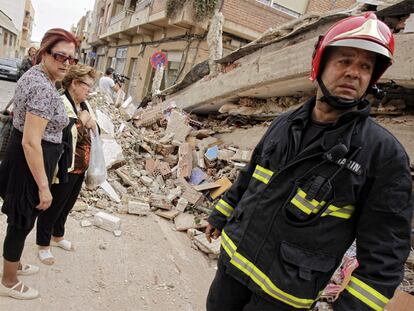 Un bombero y varios vecinos, delante de los escombros a los que quedó reducido un edificio de la calle del Infante don Juan Manuel.