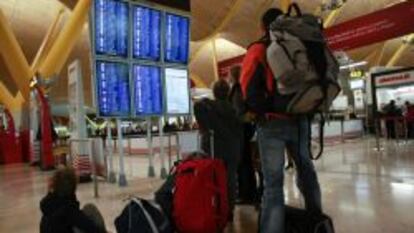 Varios pasajeros consultan los horarios de embarque en la terminal 4 de Barajas.