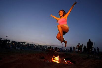 Una joven salta una hoguera en la playa de la Malvarrosa de Valencia, durante la celebración de la noche de San Juan.