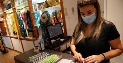 La encargada de una tienda de ropa ordena mascarillas en el mostrador de su local en Barcelona.