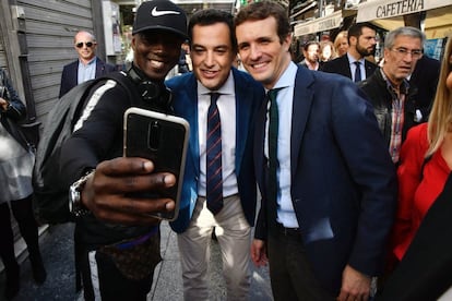 El presidente del Partido Popular, Pablo Casado (d), junto al candidato a la Presidencia de la Junta de Andalucía para las próximas elecciones autonómicas, Juanma Moreno (c), se prestan a hacerse un selfi con un joven mientras pasean por el centro de Almería.

