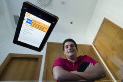 El ingeniero de telecomunicaciones Jesús Ruiz posa hoy en Málaga detrás de un cristal con la aplicación móvil que permite a particulares y empresas concentrar todas sus vías de comunicación en un solo paquete, y que pretende ser el sustituto de las clásicas tarjetas de visitas de cartón.