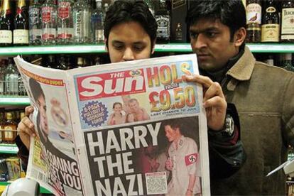 Dos londinenses leen el diario <i>The Sun,</i> con el príncipe Enrique disfrazado de nazi en la portada.