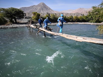 Trabajadores de salud cruzan el río Camaná para vacunar a ancianos contra COVID-19, en Arequipa, sur de Perú.