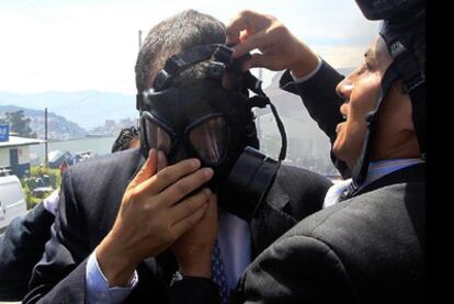 Un escolta ayuda al presidente Correa a colocarse una máscara antigás durante la revuelta de los policías.