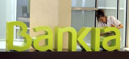 Una operaria limpia el logo de Bankia. EFE/Archivo