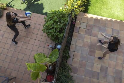 Marina y Rita practican voleibol utilizando como red la valla que separa los patios de sus casas en Vilassar de Mar, Maresme (Barcelona)